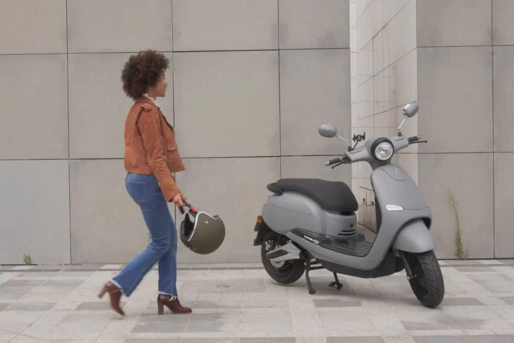 Une femme qui va vers son scooter électrique